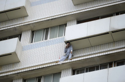 A patient sits outside a hospital building in Changsha, Hunan