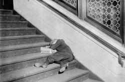 historicaltimes: A young newsboy asleep on a set of stairs with