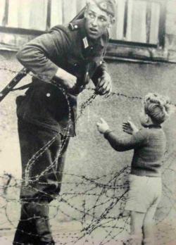 historicaltimes:  East German soldier helps a little boy sneak