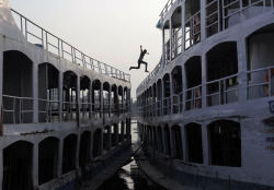 autosafari:  A man jumps from boat-to-boat by the river Buriganga