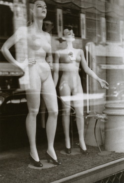 Two female mannequins stand undressed in a windowshop front in