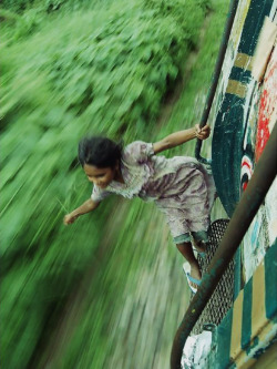 truangles:  A Bangladeshi girl hangs on to the side of a train,