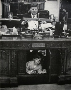 historicaltimes:  JFK Jr. peers out from the panel in his father’s