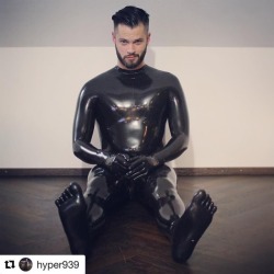 A deactivated latex-covered male sex robot looking at you like