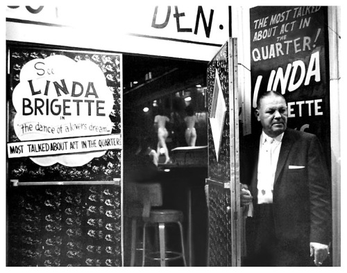 Vintage mid-60’s press photo features a rough-looking doorman inviting patrons to see Linda Brigette perform her “dance of a lover’s dream” routine at a nightclub in the heart of New Orlean’s famed ‘French Quarter&rsquo
