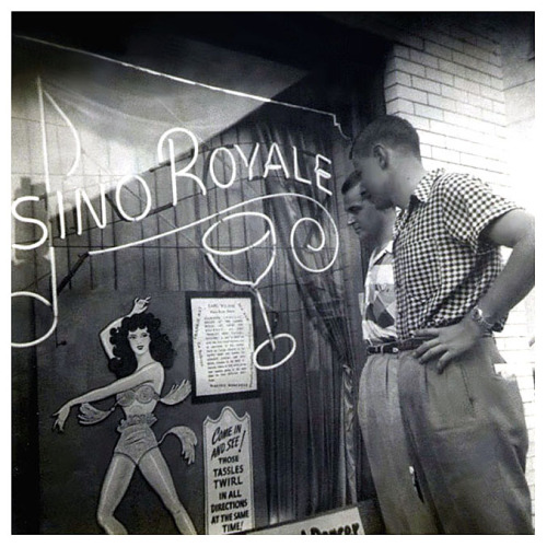 Vintage press photo from 1951 shows young males browsing the window details of the ‘Casino Royale’; a nightclub located in the French Quarter of New Orleans.. The venue was run by a popular local dancer named: Stormy (aka. Stacey Lawrence)..