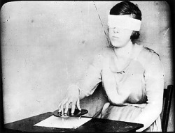  Mary Evans - A girl, blindfolded, uses the planchette with a