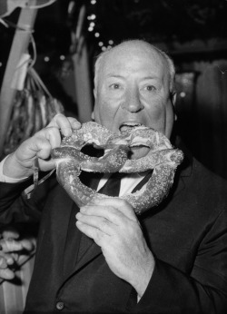 the60sbazaar:  Alfred Hitchcock tucks in to a giant pretzel 