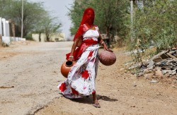 fotojournalismus:A woman carries earthen pots to fill them with