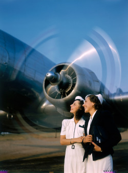 natgeofound:  Two young women stand near a turning aircraft propeller,