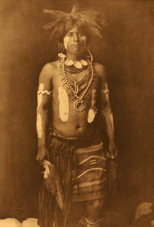 martialnudity:I’d love to know about the symbolism of his neckless and knife-feather. Is he a shaman or a warrior?
