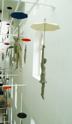 architizer:   Hang In There! Figures Dangle From Umbrellas Inside