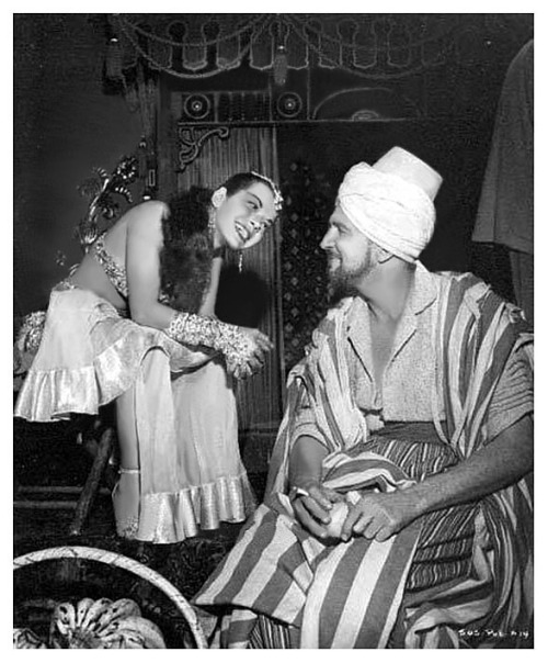 Nejla Ates takes a break with actor Vincent Price, during the filming of Howard Hughes’ 1955 film: ‘Son Of Sinbad’..  Nejla played a dancer in the marketplace that briefly distracts Price’s character (“Omar Khayyam”)