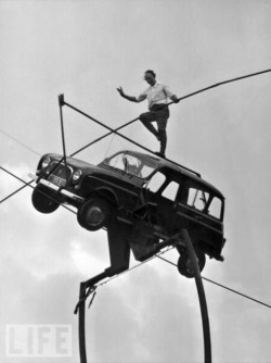 A high wire expert balances on the roof of a Renault car, which