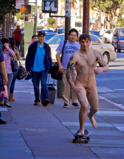 A hot picture of a young male skate boarding naked down a sidewalk.
