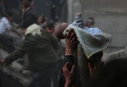 Men hold up a baby saved from a pile of rubble. Damascus, Syria,