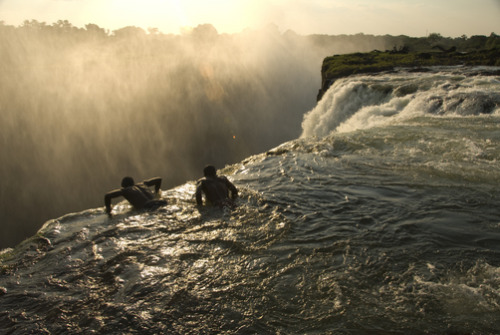 unrar:  Looking over the edge of Victoria Falls from a swimming hole, Zambia, Annie Griffiths. 