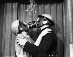 memories65:  A couple wearing gas masks kisses under mistletoe,