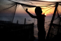 fotojournalismus:  A Palestinian child plays with a fishing net