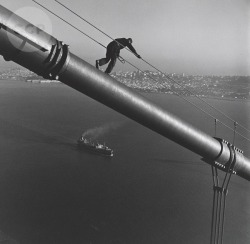 historicaltimes:  Maintenance worker walking down the cable of