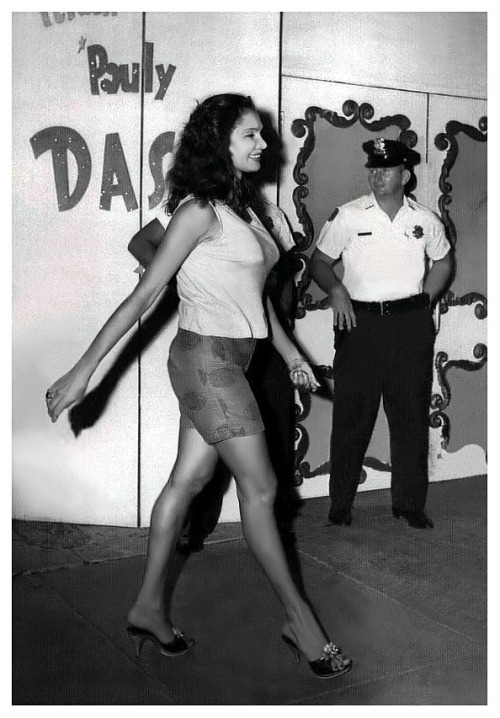 Danielle Dao Tien      aka. “The Eurasian Beauty”.. Vintage press photo dated from 1962 features Ms. Dao Tien walking past Miami Beach police officers.. In late June, a number of nightclubs in the Beaches area were found to be in violation of