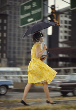 natgeofound:  A woman in a yellow dress uses an umbrella to keep