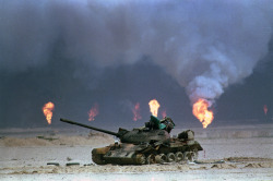 A destroyed Iraqi tank rests near a series of oil-well fires