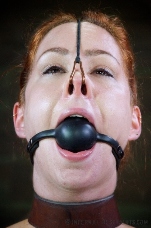Lady with red hair having a nose hook in her nose…