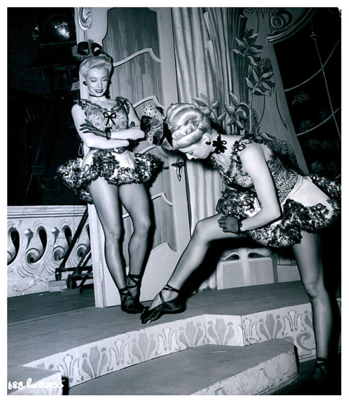 The Costello Twins Vintage publicity still features Ruth watching her twin sister adjust her hosiery, on the set of the 1948 Warner Bros. film: “April Showers”.. The twins were a well-regarded acrobatic dancing duo; but appeared in the film as part