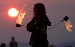 unrar:  Krissy Humphreys performs with fire at sunrise at the