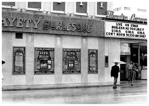 Vintage candid photo from 1969 features a rainy afternoon at the ‘GAYETY Theatre Lounge’; located on Collins Avenue (at 20th Street) in Miami Beach, Florida.. Anne Howe appears on a lobby poster as the week’s Featured Attraction..