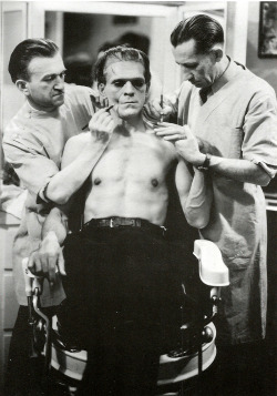 Boris Karloff undergoing make-up application during the filming