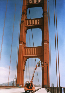 natgeofound:  A man repairs a light on the Golden Gate Bridge