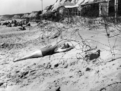 A woman sunbathes on a wartime bank holiday surrounded by barbed