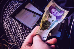 A young Iranian rolls a joint on a 5000 Toman banknote, featuring