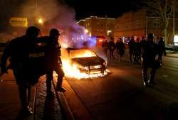 politics-war:  Police officers walk by a burning police car during