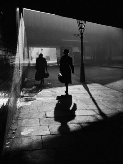  Women walking down sidewalk at night London 1950s  Photo: Alex