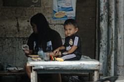 Kid looks on as his mother feeds him. Bandung, Indonesia.