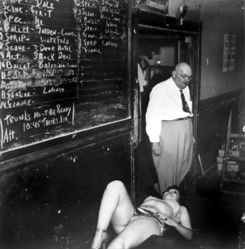 alterneaze: (via This Week’s Weegee #81) A showgirl takes a break Backstage; at an unidentified theatre.. The large chalkboard lists the sequence of acts for the entire Burlesque show.. It also lists a notice: “Trunks Must Be Ready..” 