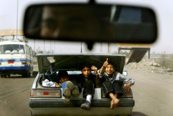 xafat:  Boys wave as they ride in the trunk of a car February