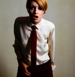 Twiggy posed wearing a white shirt, knitted tie and trousers