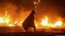 artisansknight:  A protester wearing a gas mask walks in front