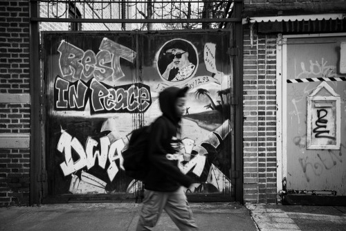 yearningforunity:  A young boy walks in front of Rest In Peace graffiti in East New York, NY.