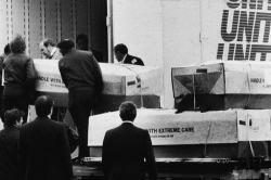 dichotomized:  Men load coffins into a moving truck for transport