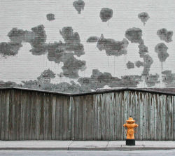 Hydrant against grey wall by Kevin Steele