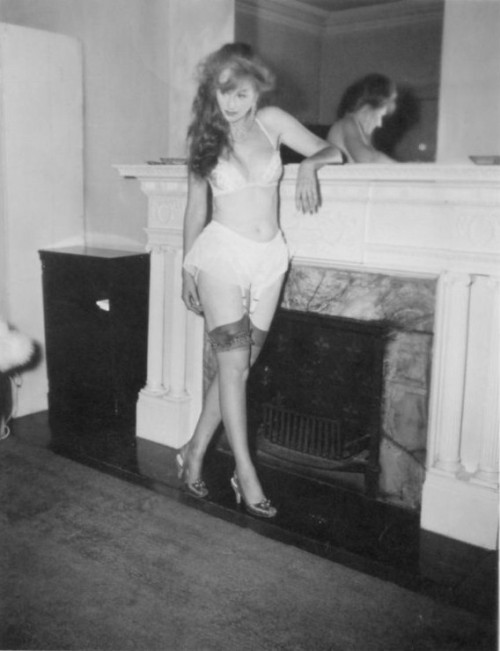 Lynne O'Neill (aka. “The Original Garter Girl”) poses by the fireplace..