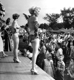 Young men ogle showgirls on the bally stage of a carnival Girlie-Show,