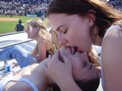 entremaliades:  Two girls tongue kissing in a crowded stadium