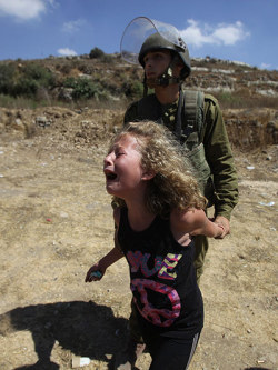  inothernews: An Israeli soldier holds a Palestinian girl back