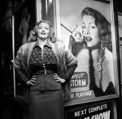 Tempest Storm poses next to one of the large lobby posters beneath